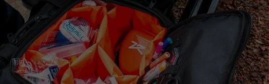 Fotografía de un maletín color negro con forro color naranja que contiene equipo médico de emergencia.