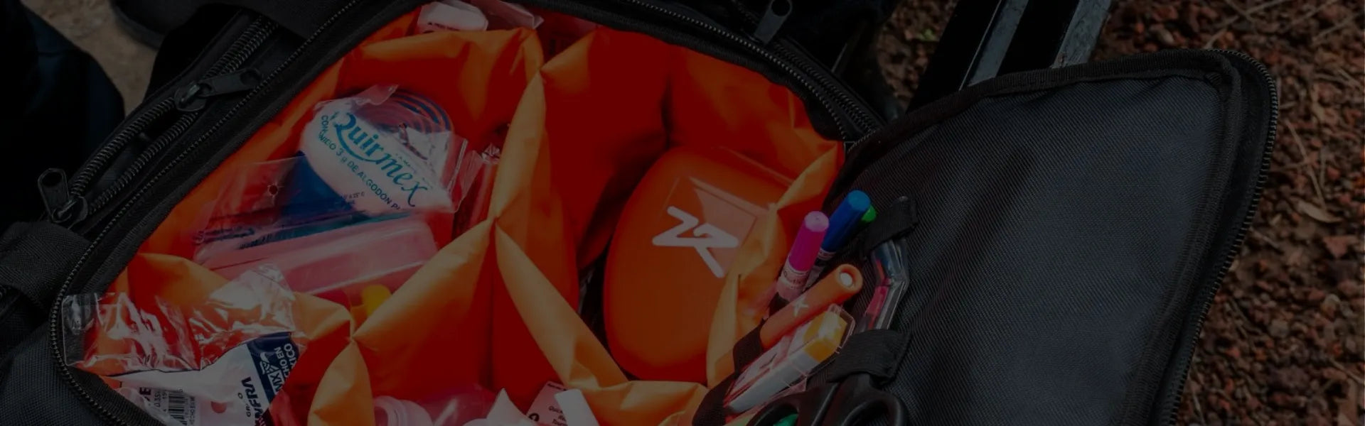Fotografía de un maletín color negro con forro color naranja que contiene equipo médico de emergencia.