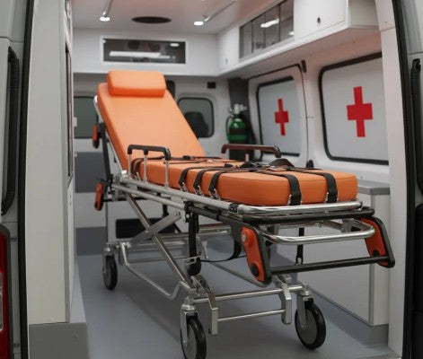 Fotografía de una camilla de emergencia color naranja con cintas color negro dentro de una ambulancia.