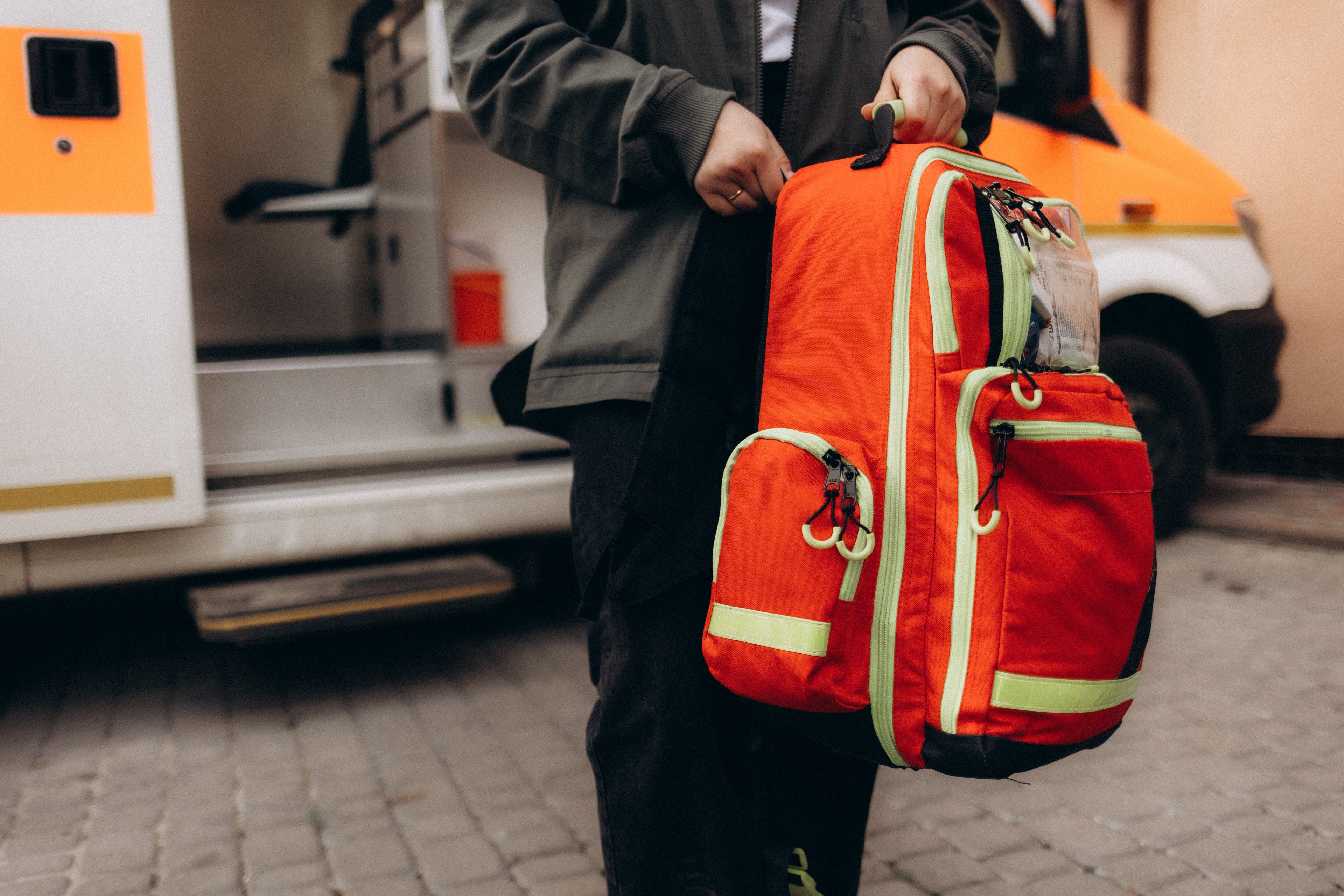 Fotografía de un profesional cargando una mochila para kits de equipo de rescate color naranja con cierres color blanco.