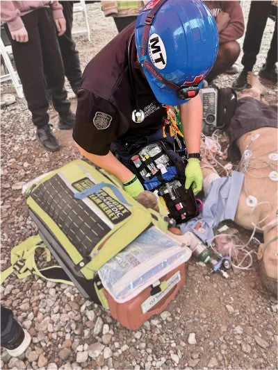 Fotografía desde arriba de una persona utilizando un casco de protección color azul brindando primeros auxilios.