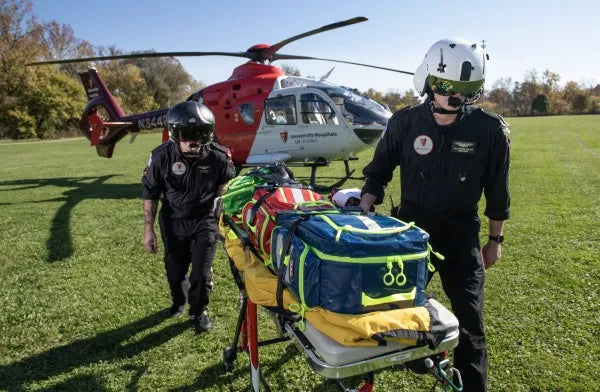 Equipo médico de emergencia: guía completa. Fotografía dos hombres caminando llevando una camilla con botiquines.