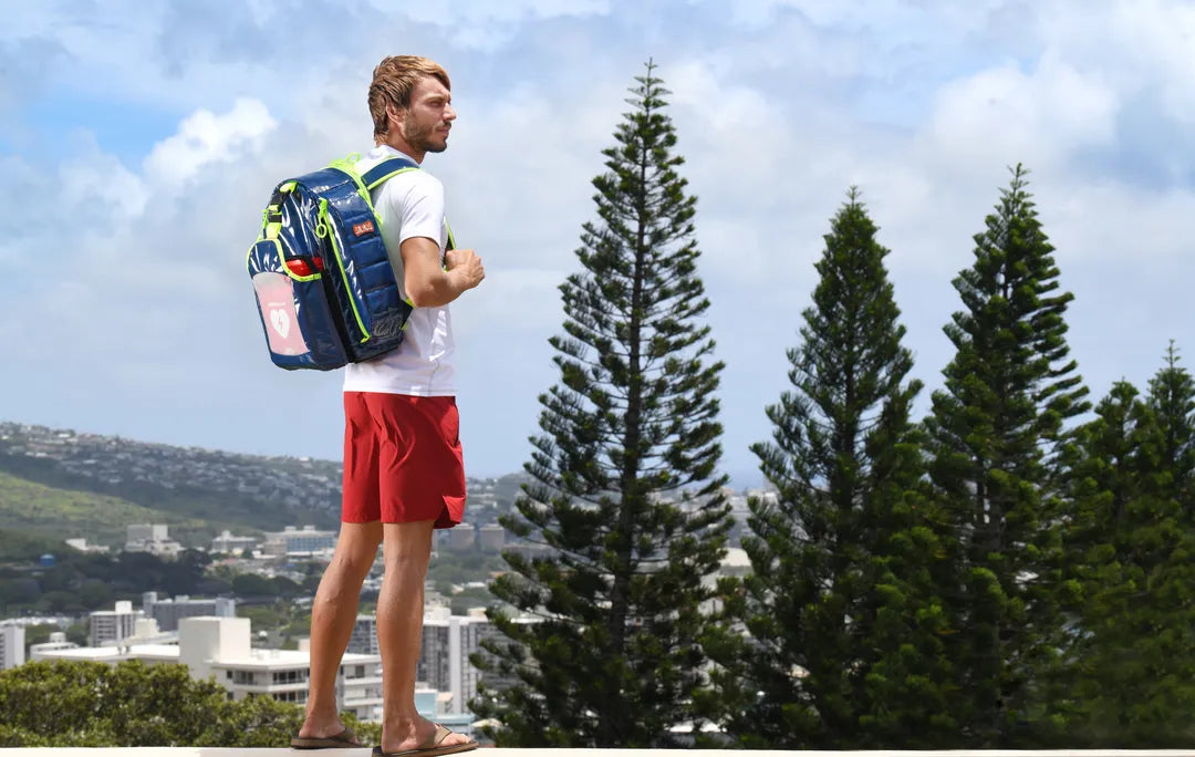 Mochilas de emergencia: Fotografía desde atrás de un hombre cargando una mochila color azul con cierres color verde.