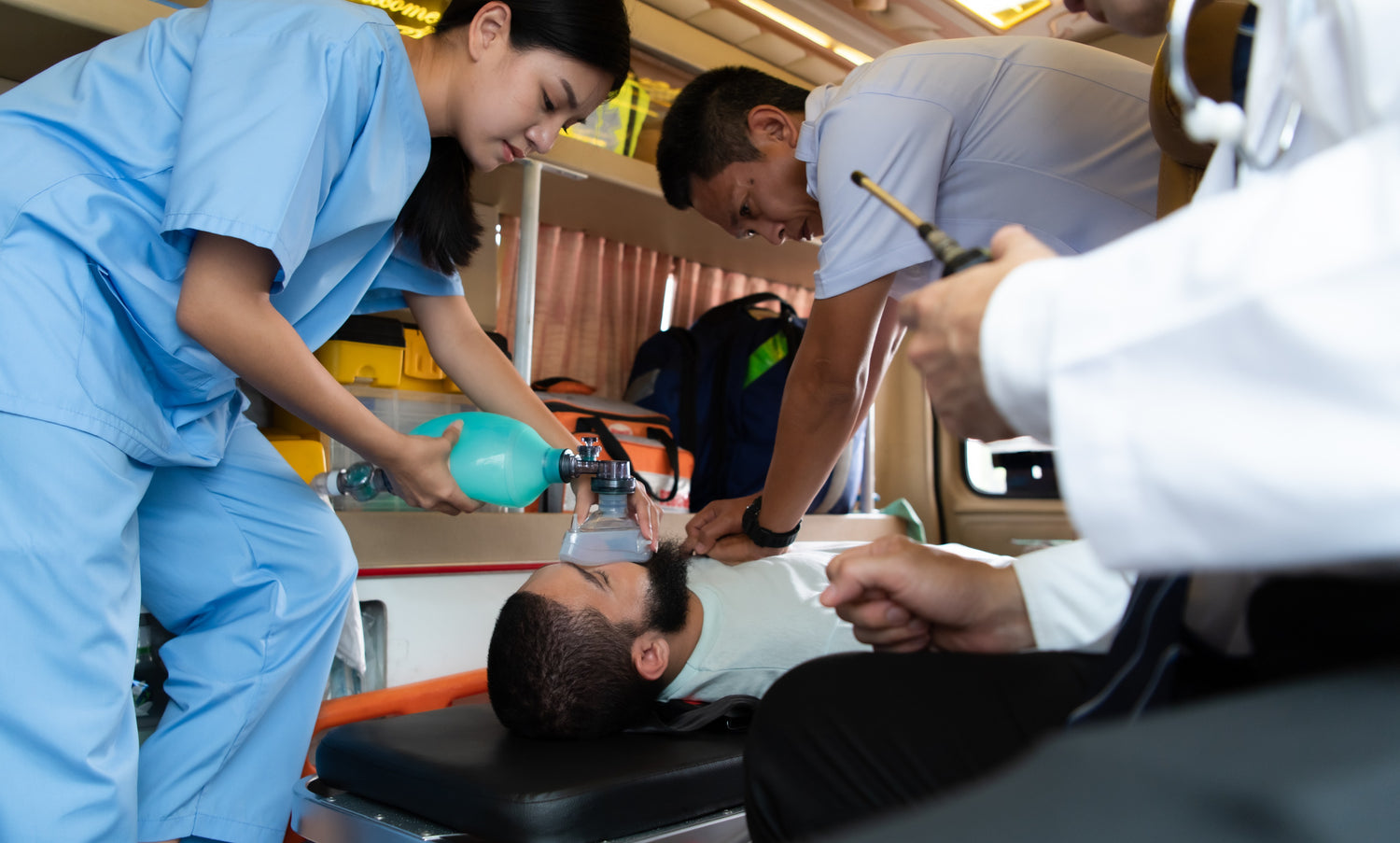 Fotografía de personal médico experto atendiendo a un paciente dentro de una ambulancia con equipos de emergencia.
